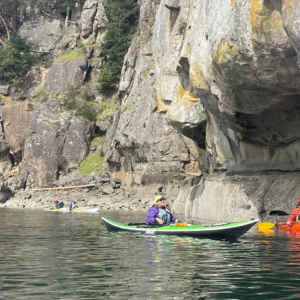 Kayakers paddling alongside dramatic sandstone cliffs on a guided 90 minute kayak tour on Saturna Island BC